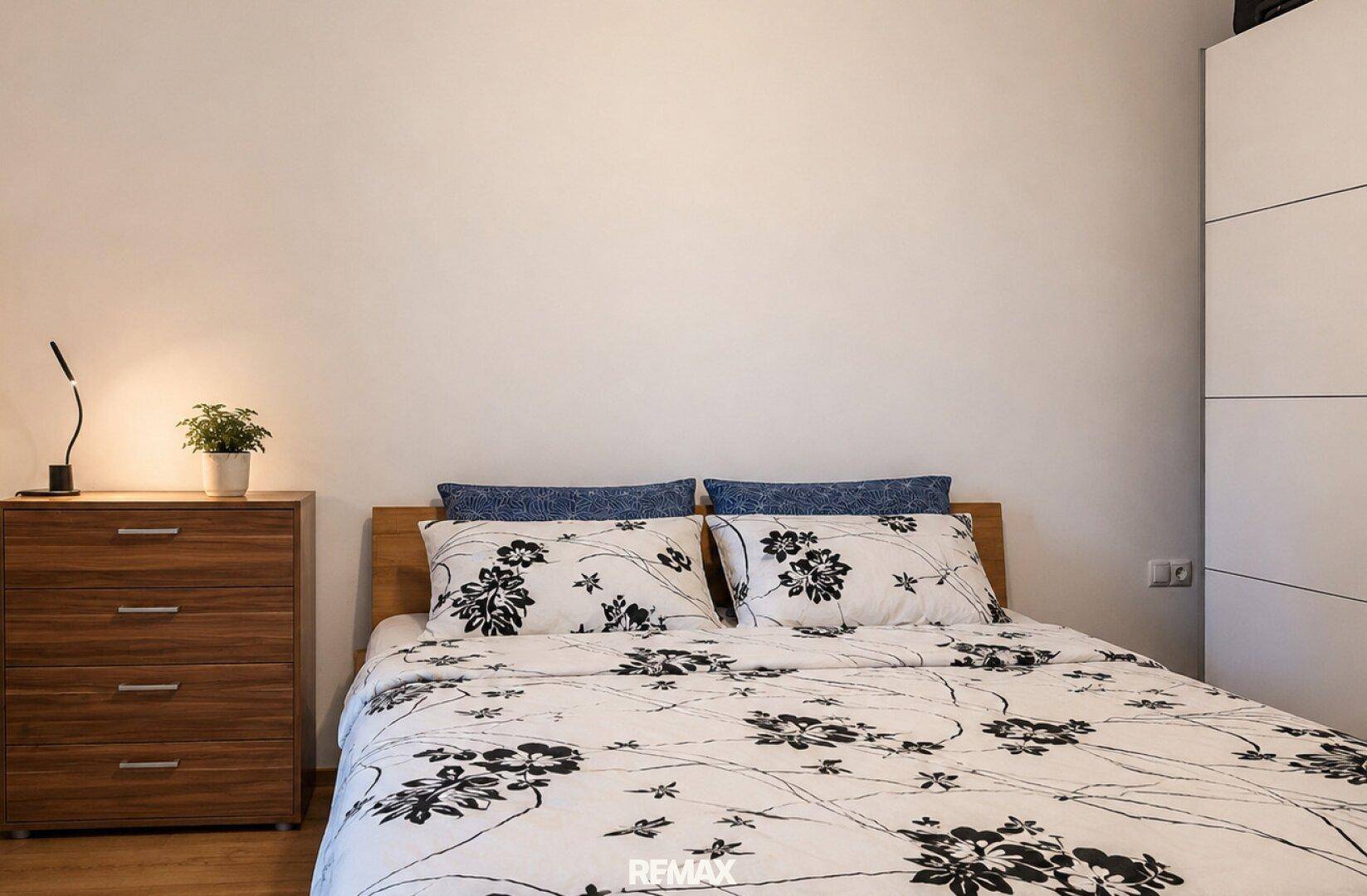 Gemütliches Schlafzimmer mit Doppelbett, Nachttisch und weißem Kleiderschrank.