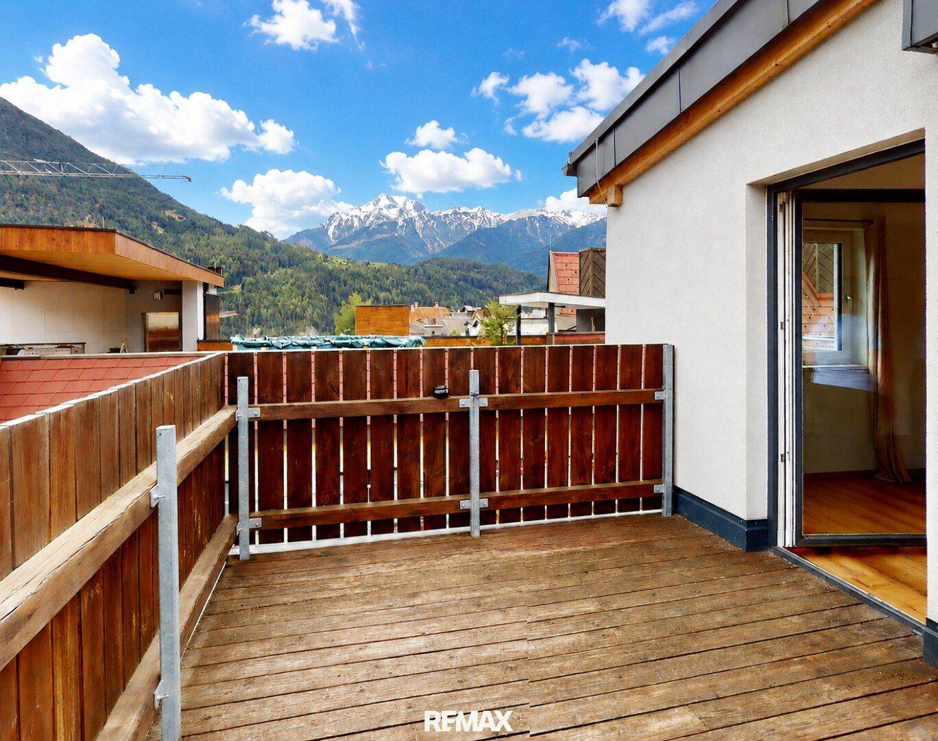 Großer Holzbalkon mit beeindruckendem Blick auf die schneebedeckten Berge.