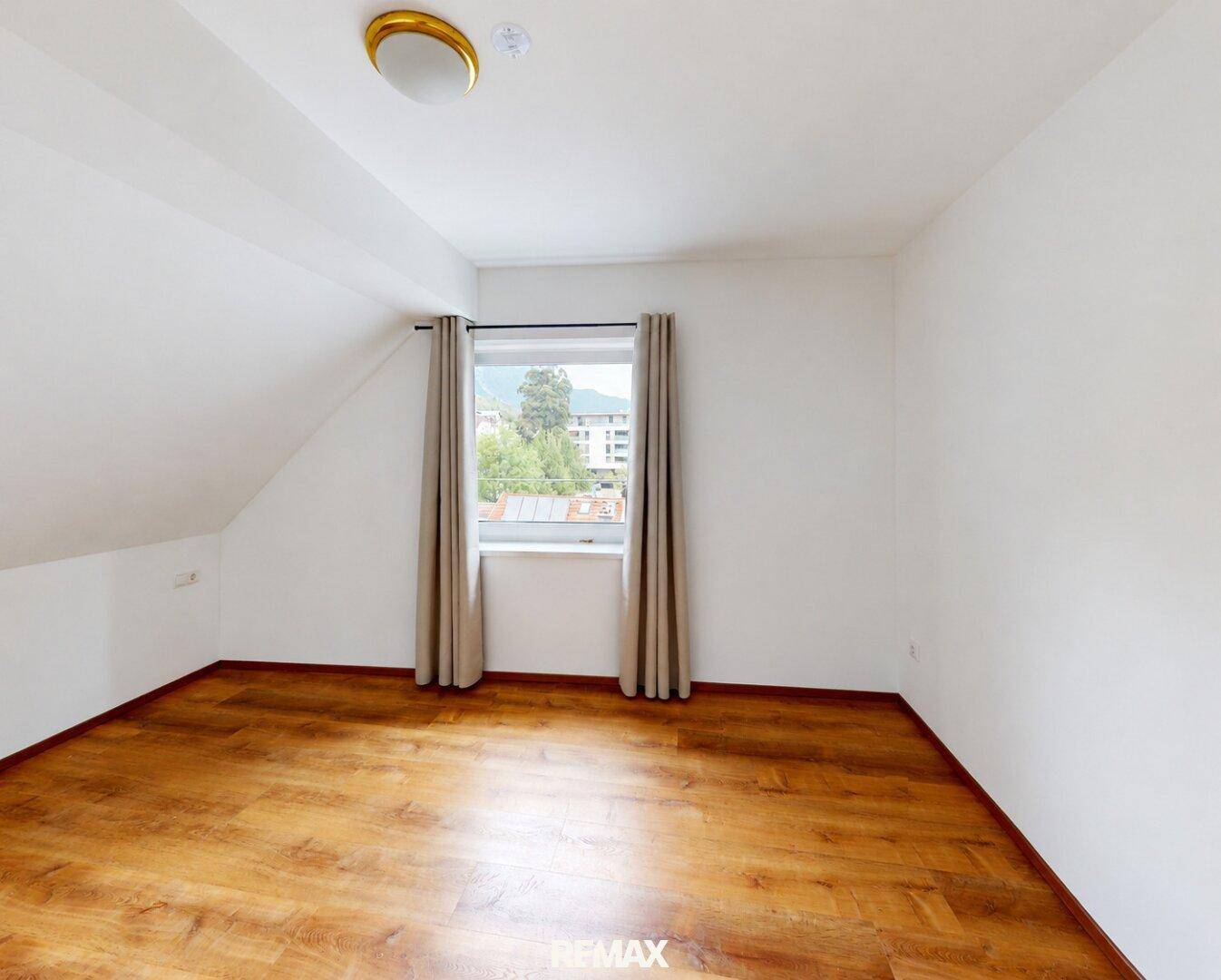 Helles Schlafzimmer mit Holzboden, Fenster und Dachschräge, ideal für individuelle Einrichtung.