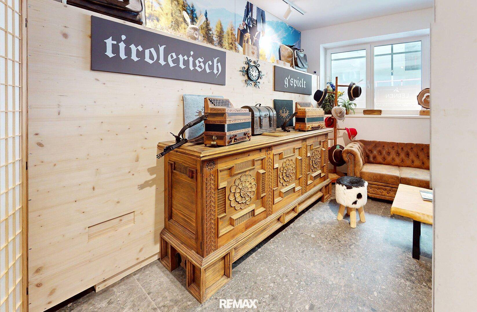Detailansicht eines traditionellen, geschnitzten Holzschranks in einem hellen Verkaufsraum mit Holzvertäfelung.