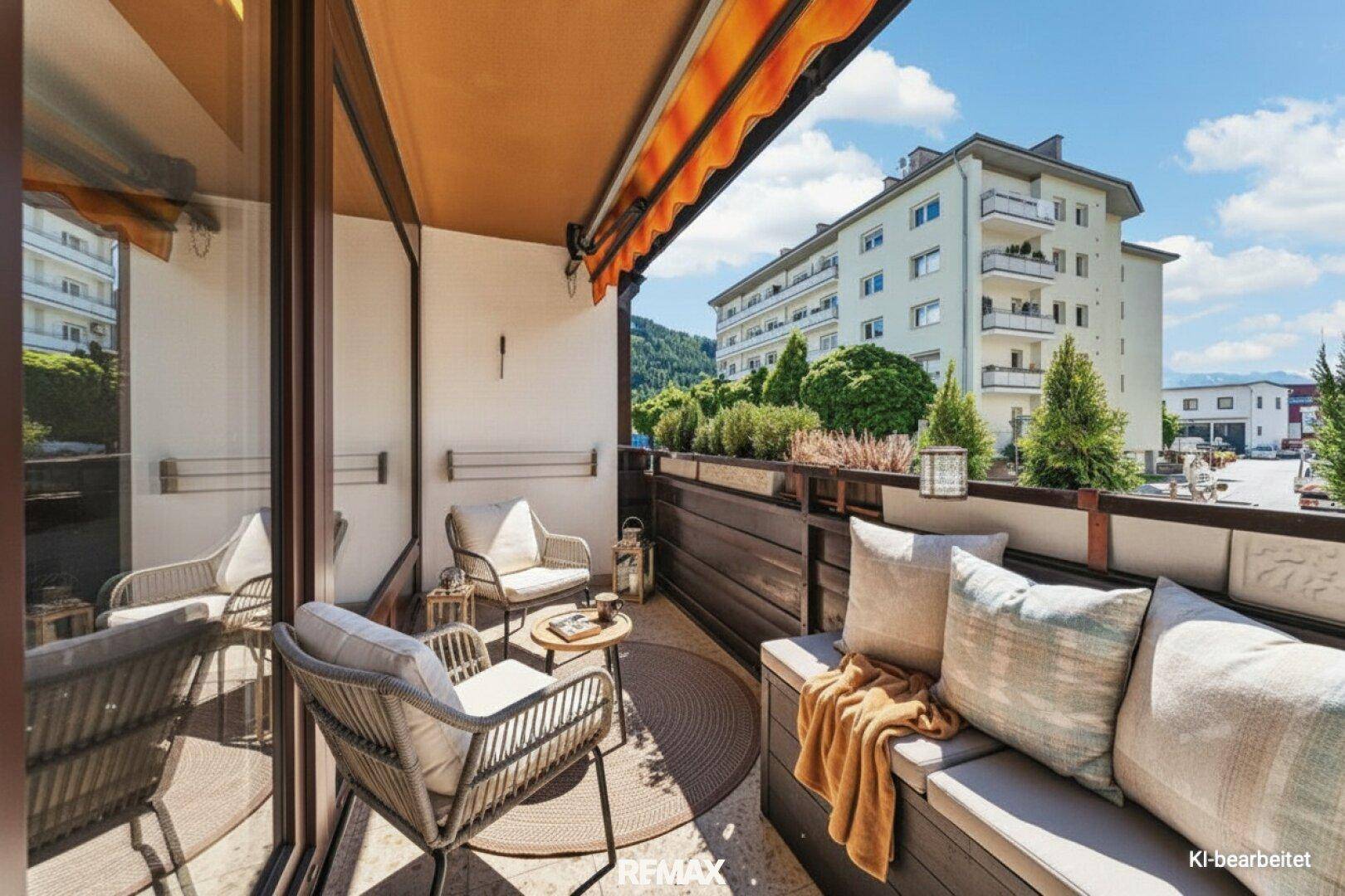 Gemütlicher Balkon mit Sitzgelegenheiten, Markise und Blick auf die umliegenden Gebäude.