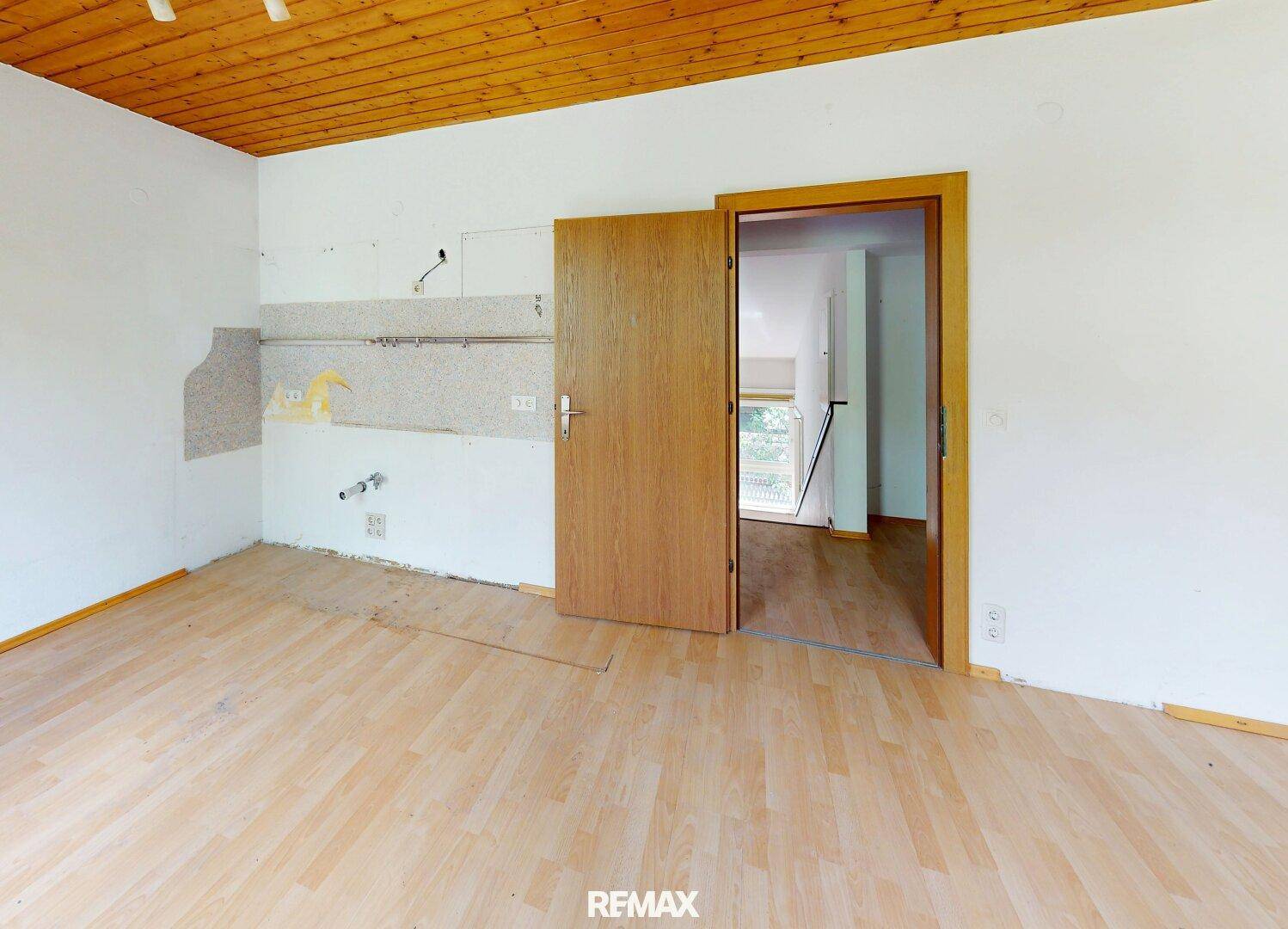 Leere Küche mit Holzboden und vorbereiteten Anschlüssen für die Kücheneinrichtung.