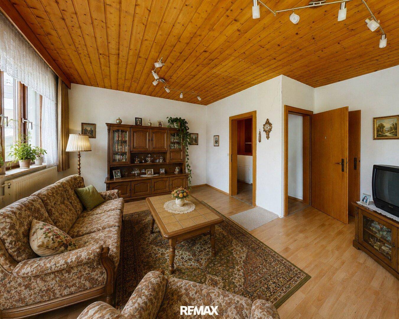 Gemütliches Wohnzimmer mit Holzboden, Holzdecke und traditionellen Möbeln.