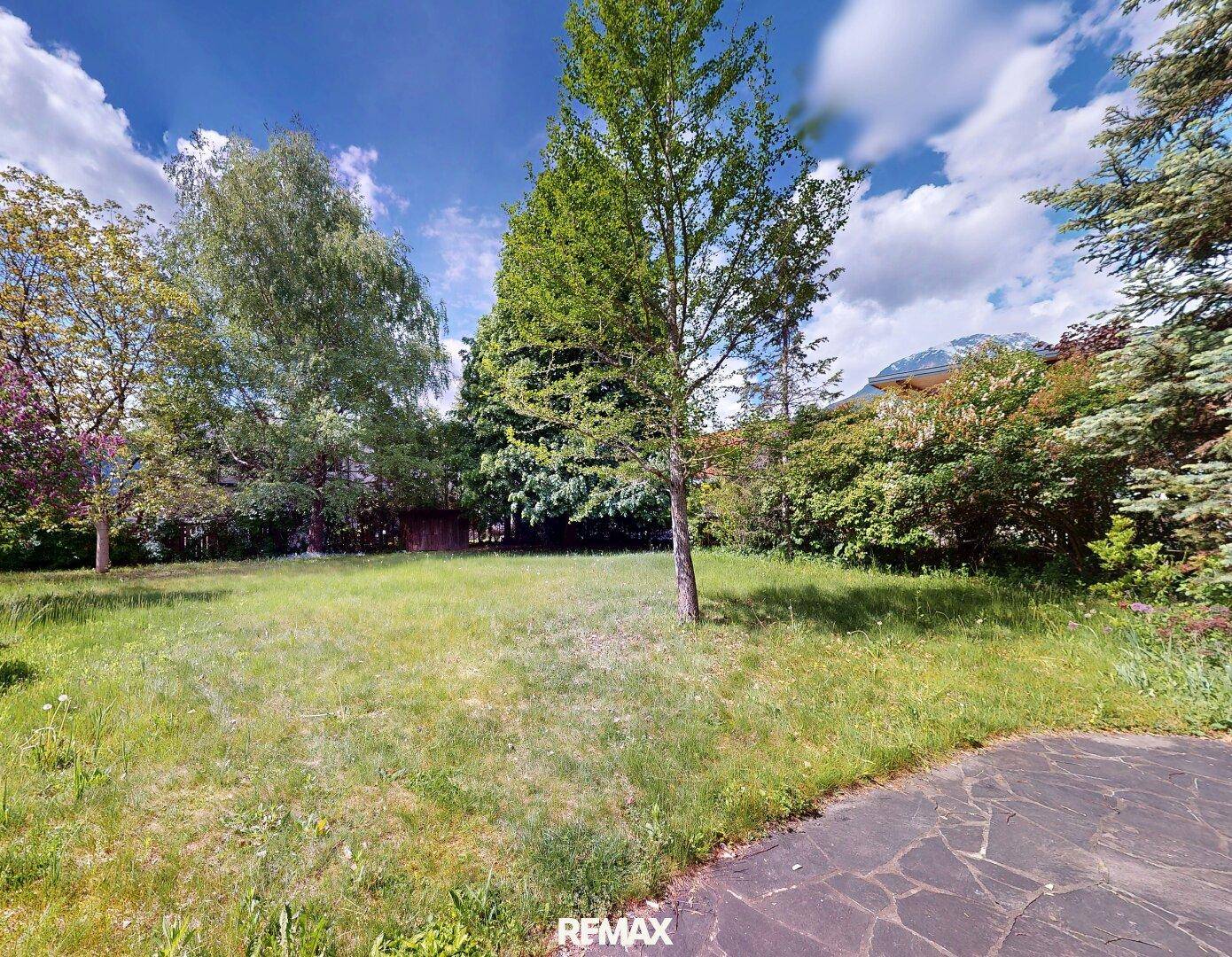Weitläufiger Gartenbereich mit Rasen, Bäumen und Blick auf die umliegende Landschaft.