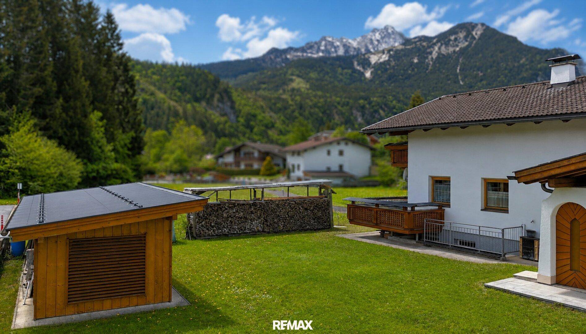 Gepflegter Gartenbereich mit Holzschuppen und Blick auf die umliegende Berglandschaft.