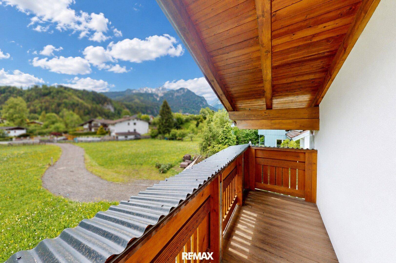 Balkon mit Holzboden und Geländer, bietet einen schönen Ausblick auf die grüne Umgebung.