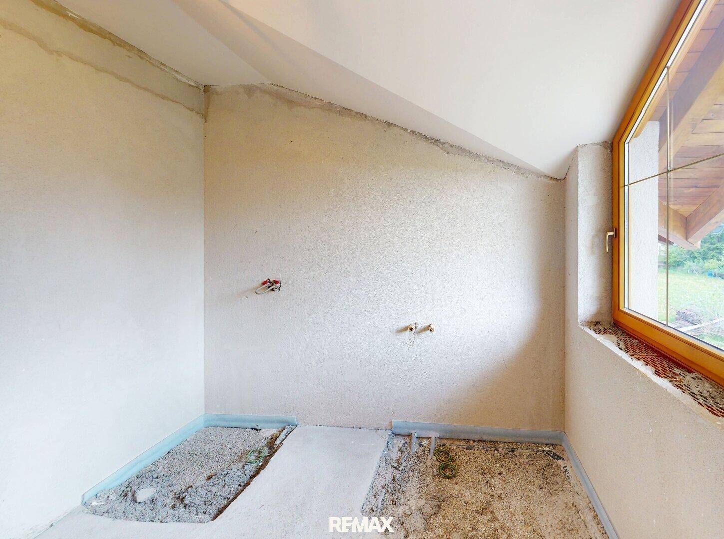 Badezimmer im Rohbau mit vorbereiteten Anschlüssen und Fenster für zukünftige Gestaltung.