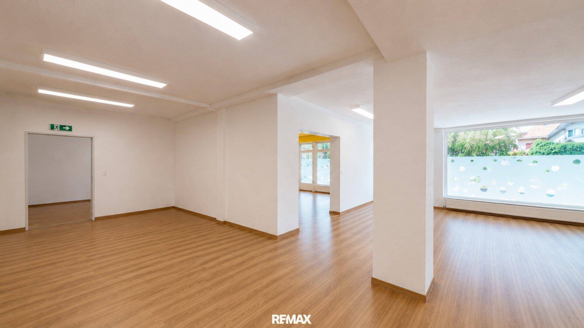Großer, heller Raum mit Laminatboden, weißen Wänden und Fenstern mit Sichtschutzfolie.