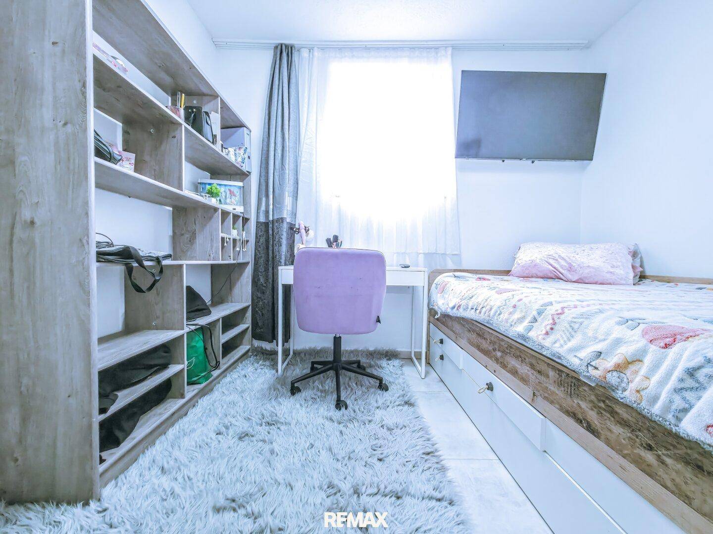 Kinderzimmer oder Gästezimmer mit Bett, Schreibtisch, Stuhl und praktischem Regal.