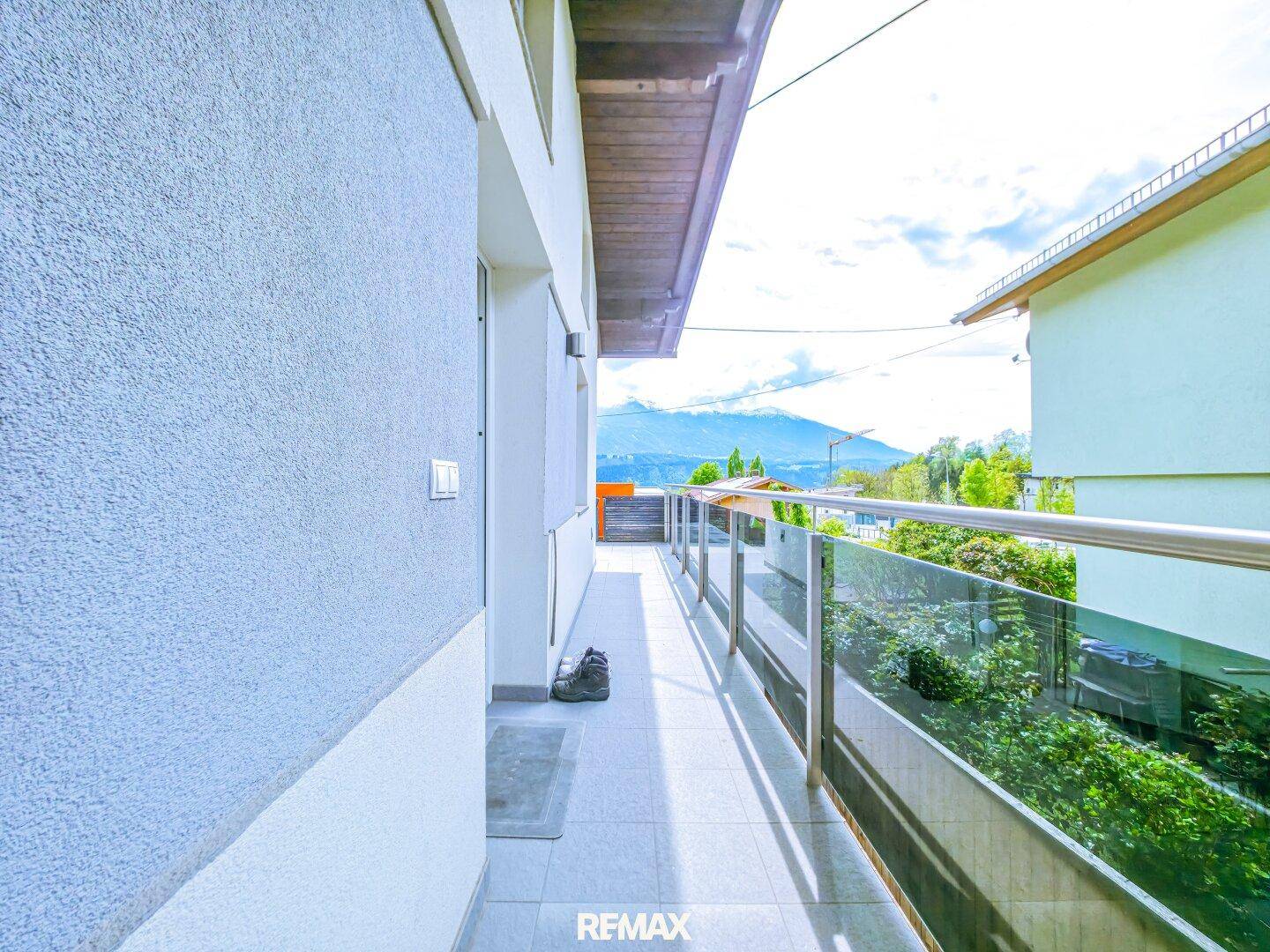 Schmaler Balkon mit modernem Glasgeländer und Blick auf die Berglandschaft.