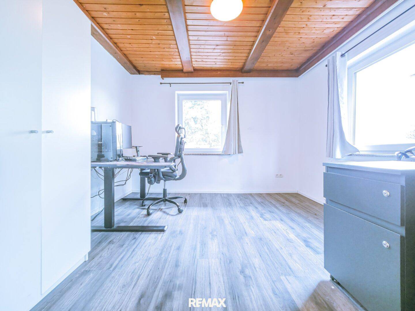 Helles Arbeitszimmer mit Holzbalkendecke, Laminatboden und Blick ins Grüne.