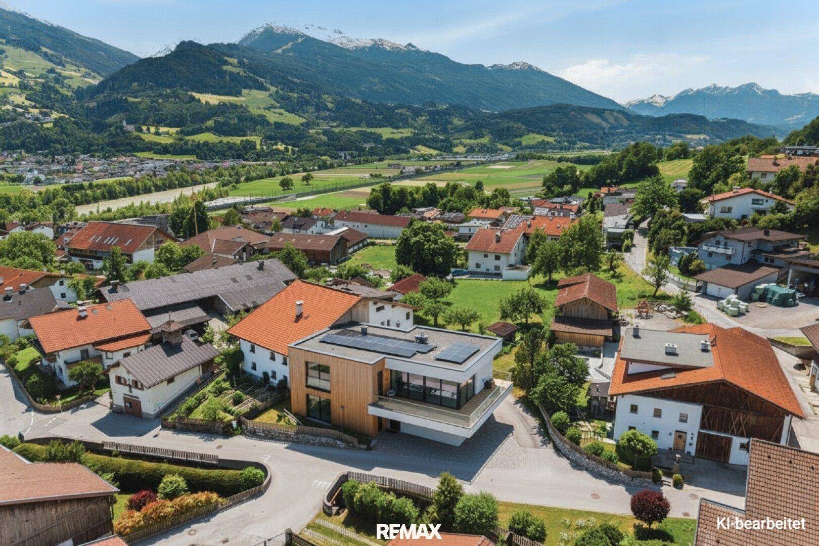 Moderne Architektur mit großen Glasflächen und Holzelementen, harmonisch in die weite Tal- und Berglandschaft integriert.