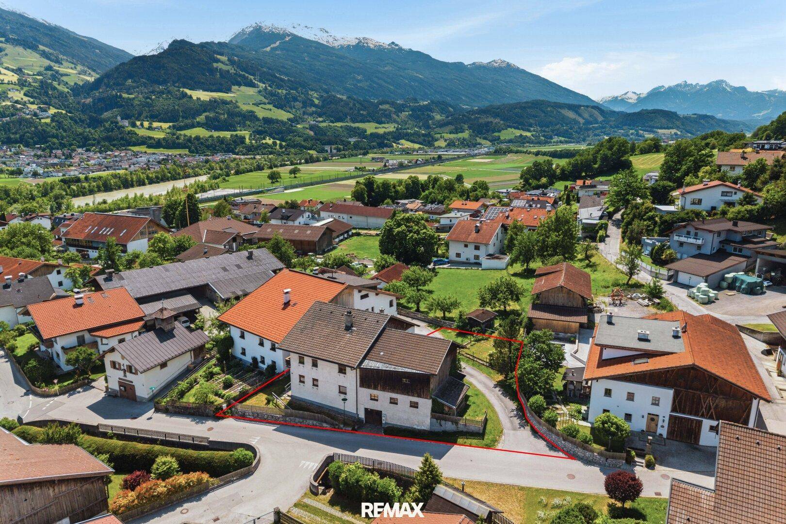 Weitläufige Luftaufnahme des Grundstücks mit roter Umrandung, Dorfansicht und weitem Talblick.
