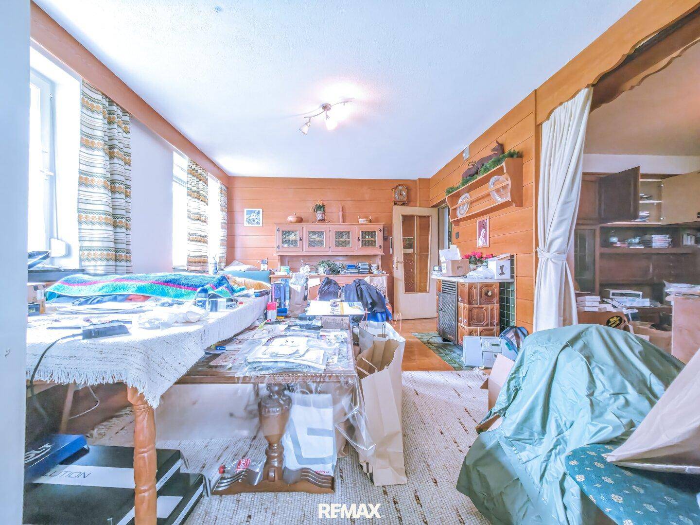 Wohnzimmer mit Holzvertäfelung, Teppichboden und vielen persönlichen Gegenständen.