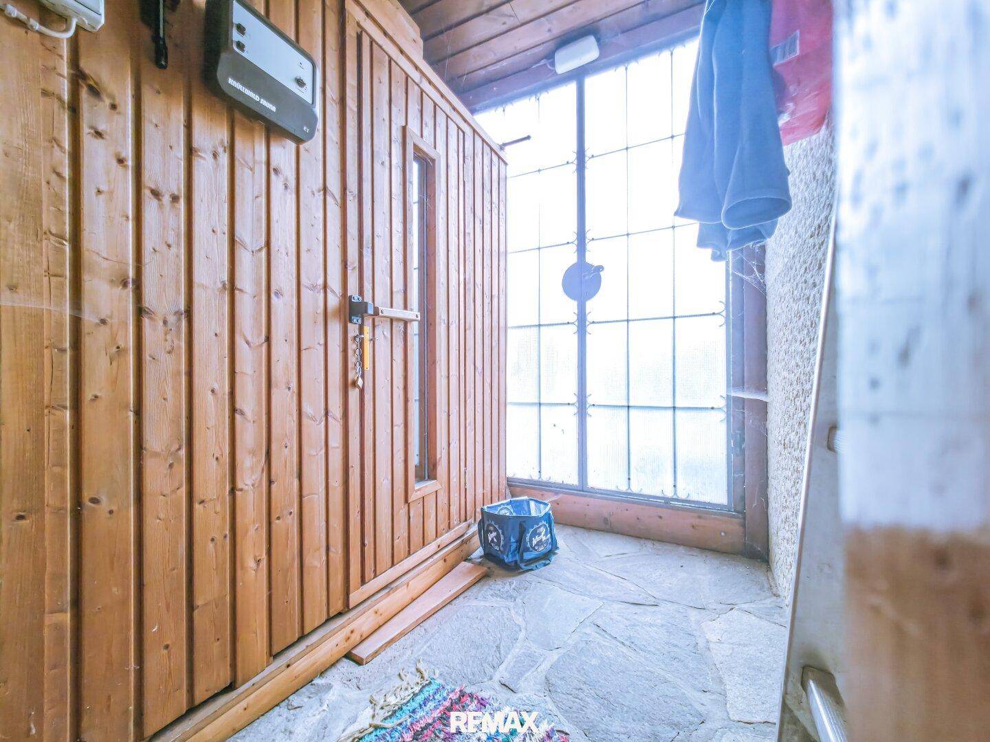 Sauna mit Holzverkleidung und Steinboden, gelegen neben einem großen Fenster, ideal zur Entspannung.