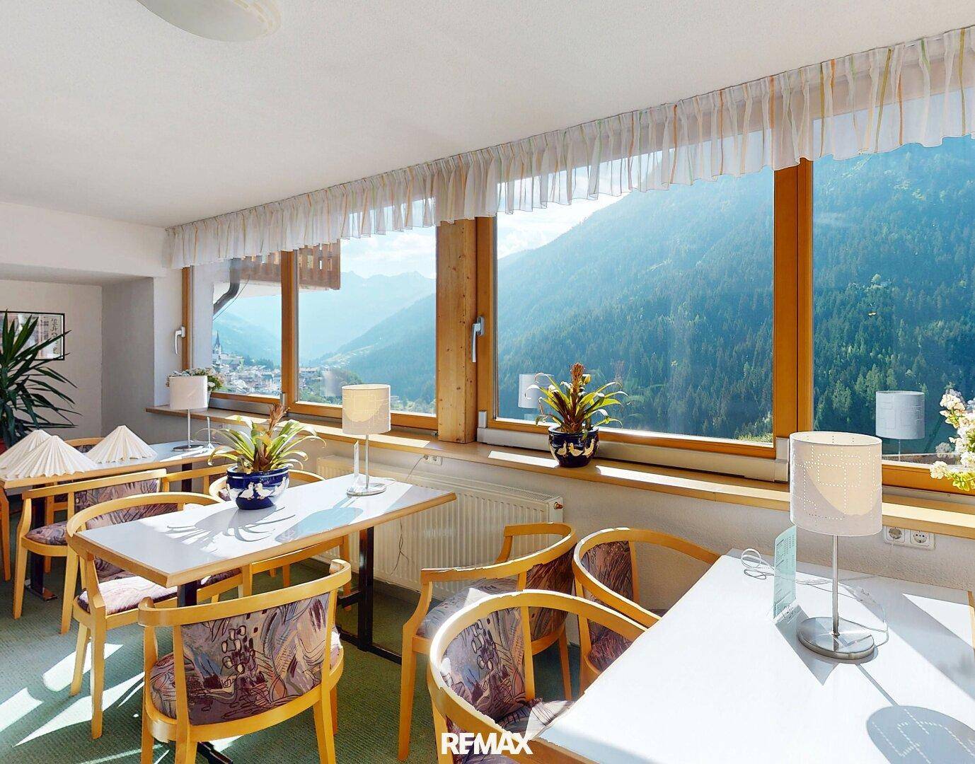 Heller Speisesaal mit großen Fenstern, die einen atemberaubenden Blick auf die Berglandschaft bieten.
