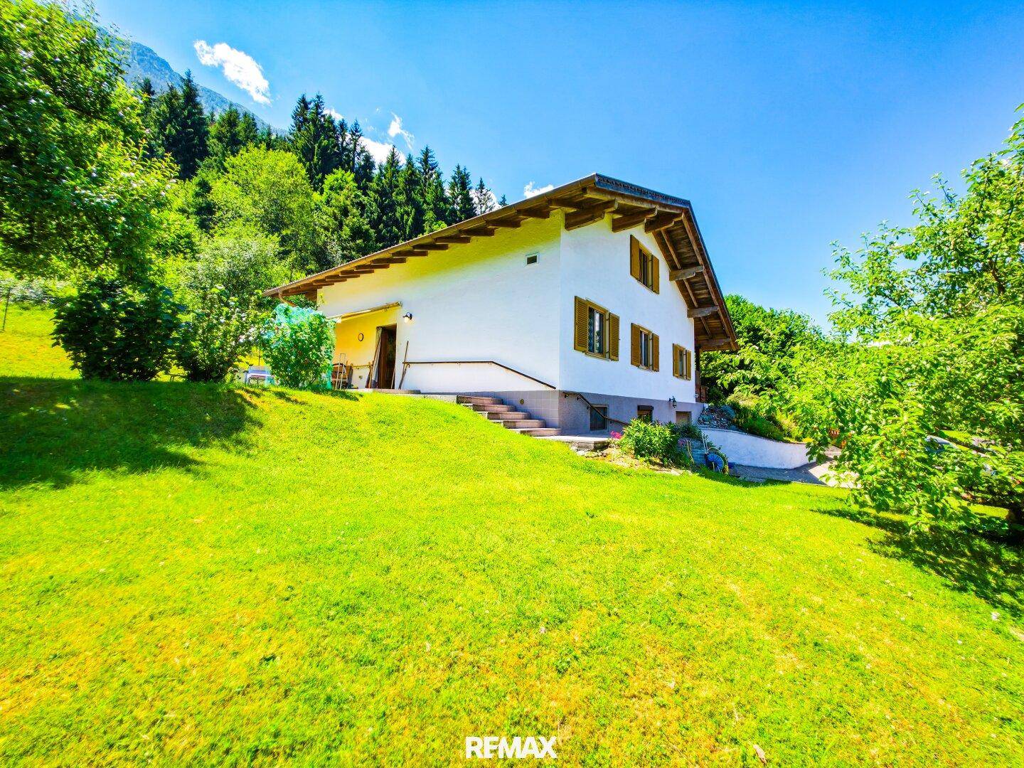 Freistehendes Haus mit weitläufigem, grünem Garten und Blick auf die umliegende Natur.