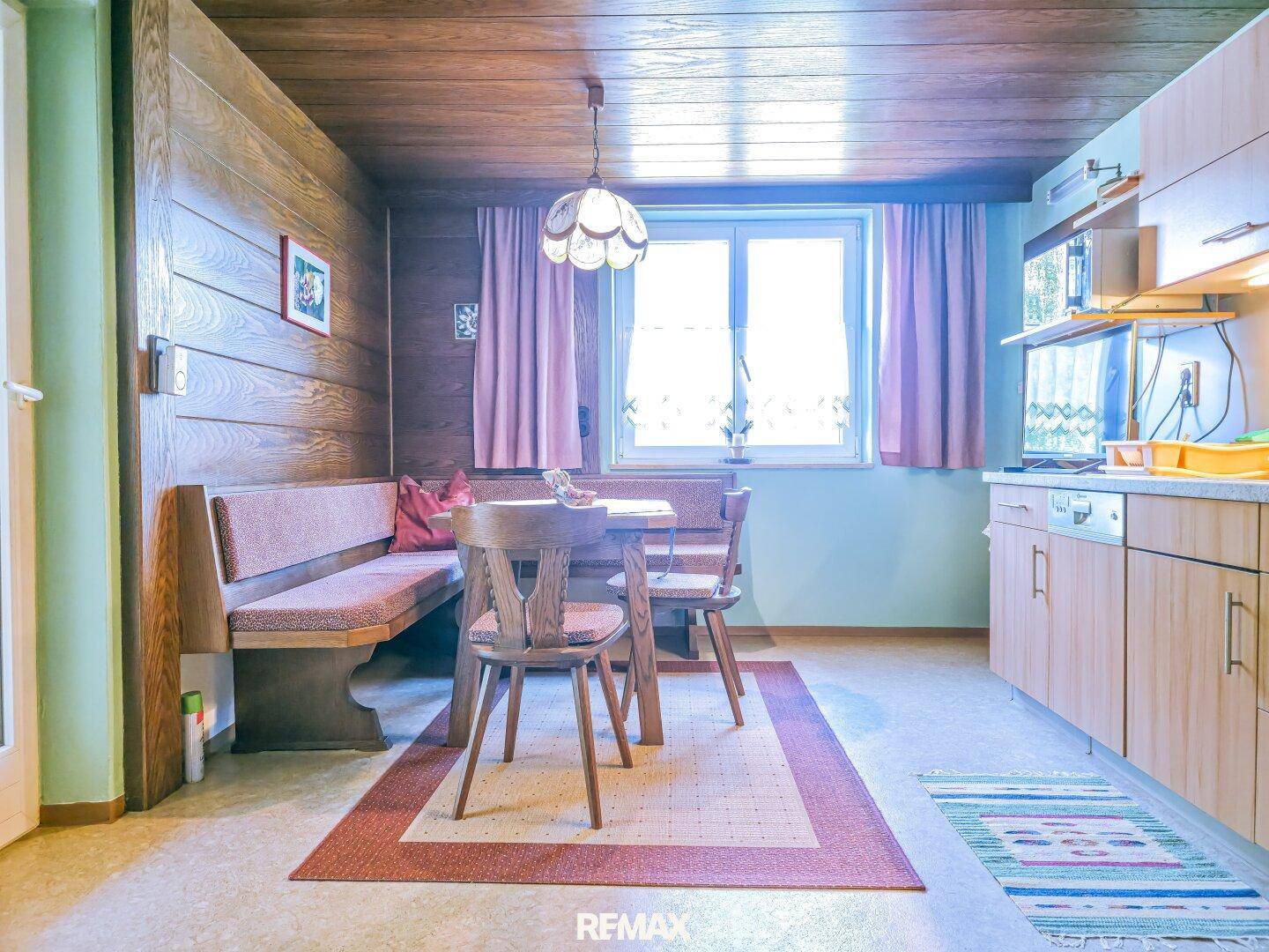 Essbereich in der Küche mit traditioneller Sitzecke, Holzmöbeln und Fenster für Tageslicht.