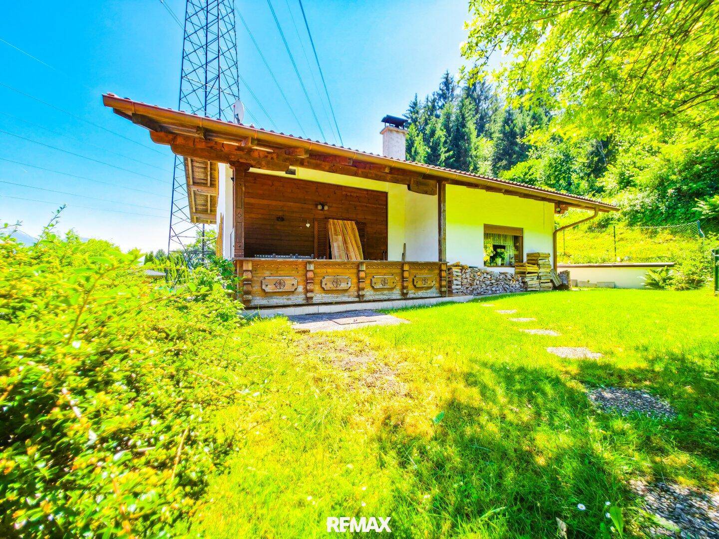 Traditionelles Haus mit überdachter Loggia, umgeben von grüner Natur und Bergblick.