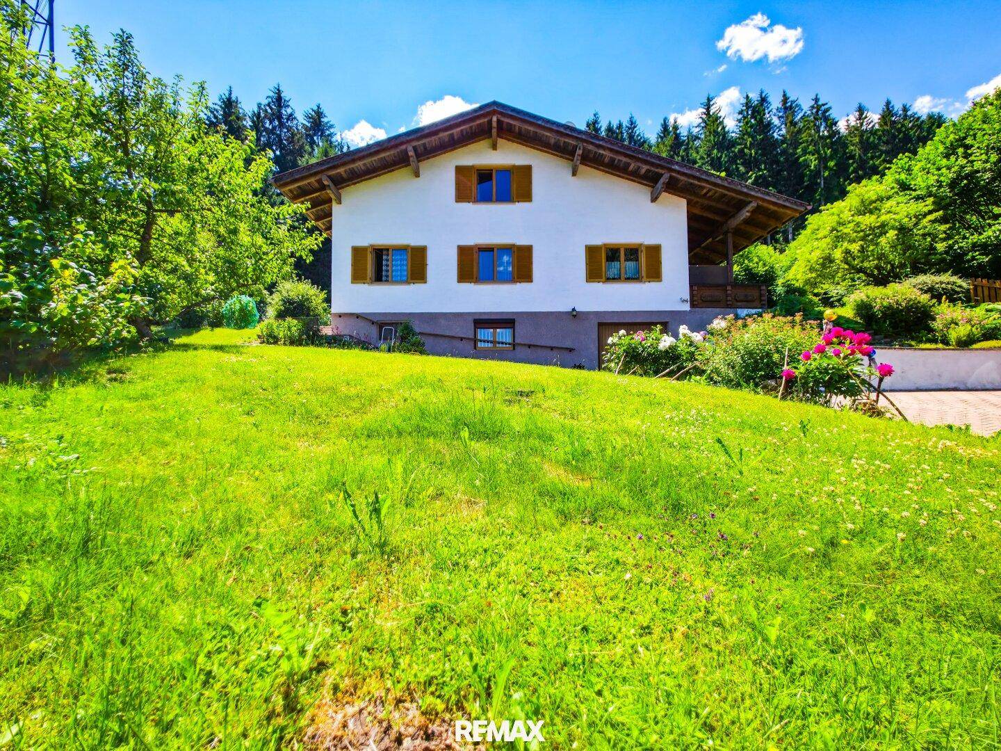 Traditionelles Einfamilienhaus mit Holzfensterläden und großem Garten in ländlicher Umgebung.