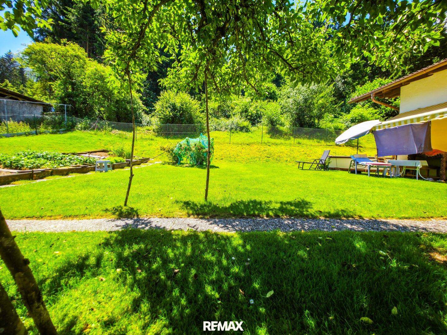 Weitläufiger Garten mit Rasenfläche, altem Baumbestand und einem kleinen Küchengarten.