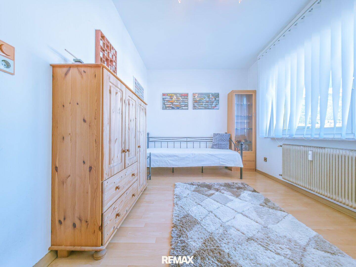 Schlafzimmer mit Holzboden, Einzelbett und traditionellem Holzschrank.