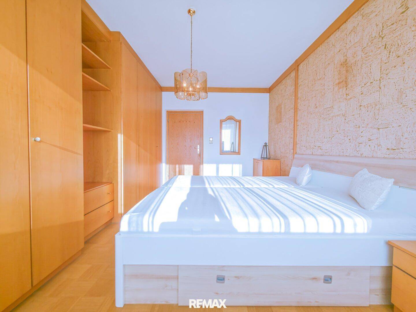 Schlafzimmer mit Einbauschränken, Doppelbett und hellem Holzboden.