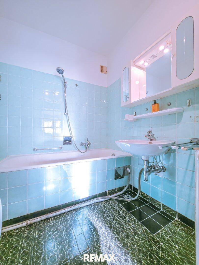 Badezimmer mit Badewanne, Waschbecken und blauen Wandfliesen.