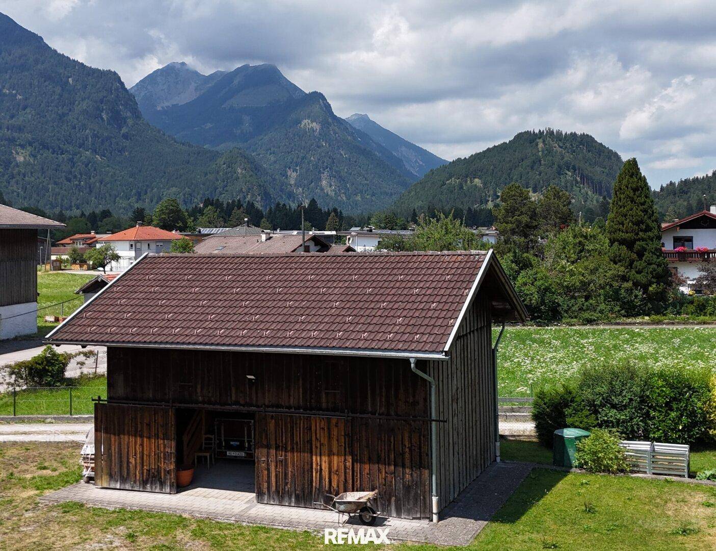 Rustikales Nebengebäude mit Holztüren und Blick auf die umliegende Berglandschaft.