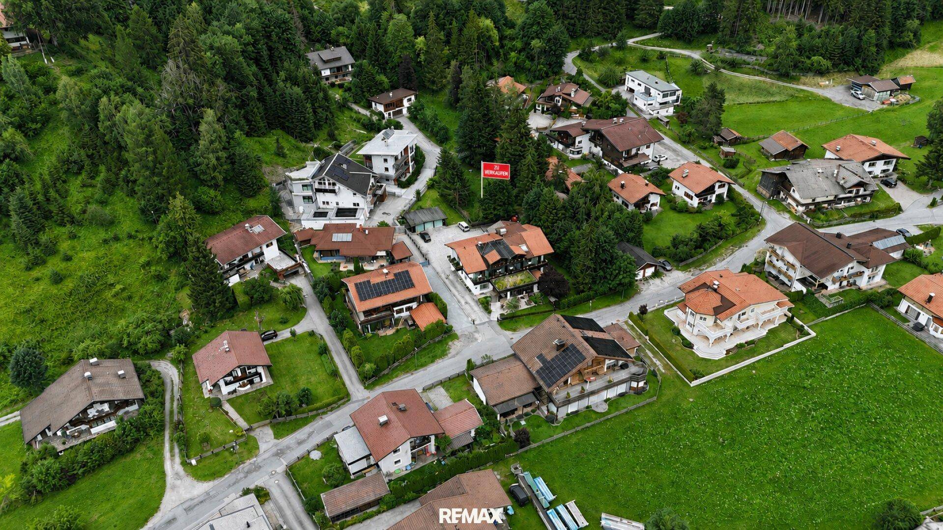 Luftaufnahme eines Wohngebiets mit Einfamilienhäusern, Straßen und viel Grün.