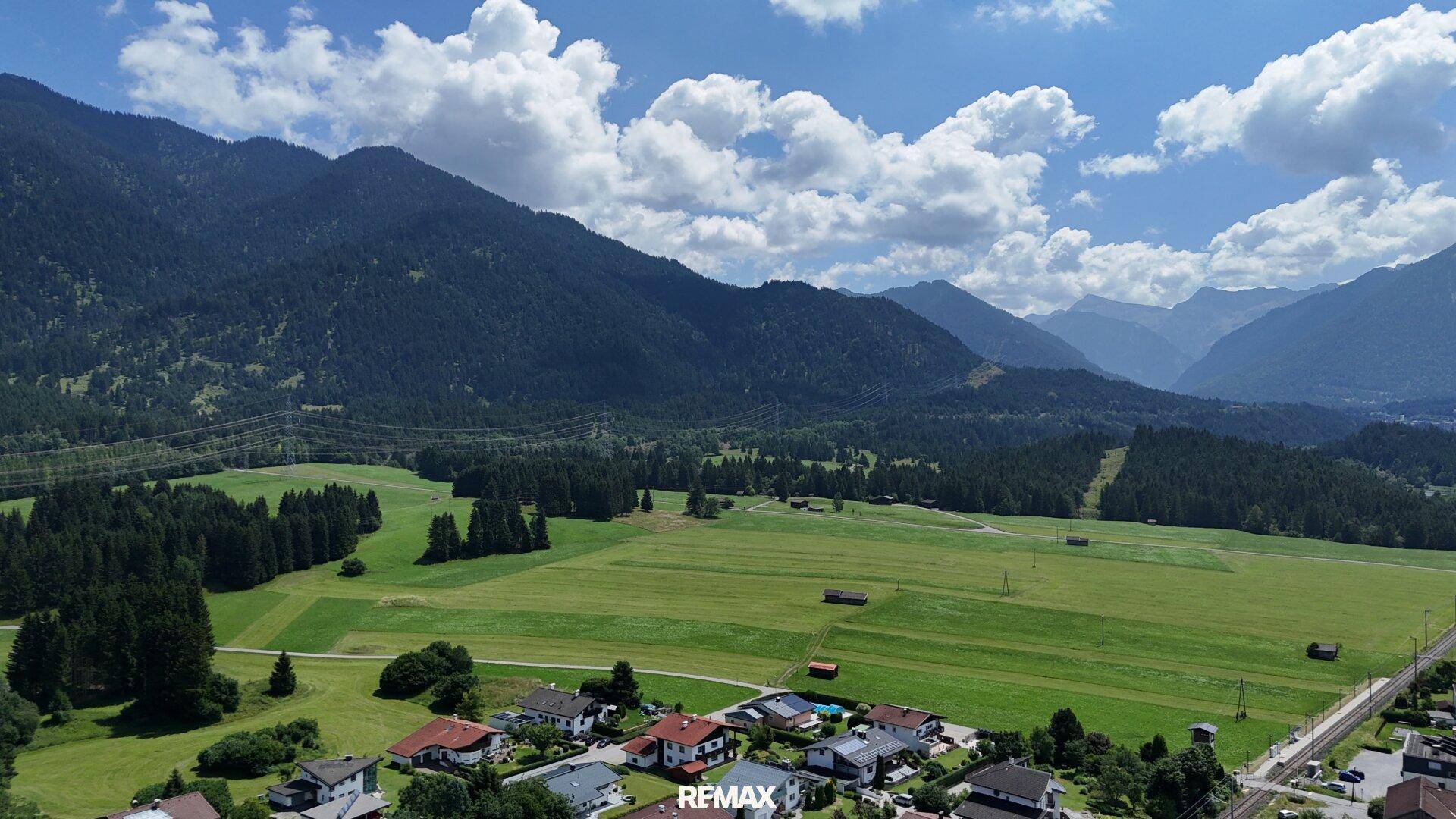 Panoramablick über grüne Felder, Wälder und eine kleine Wohnsiedlung in den Bergen.