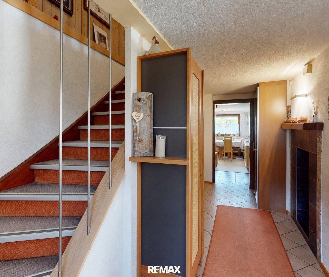 Heller Eingangsbereich mit Holztreppe, Fliesenboden und Zugang zu weiteren Räumen.