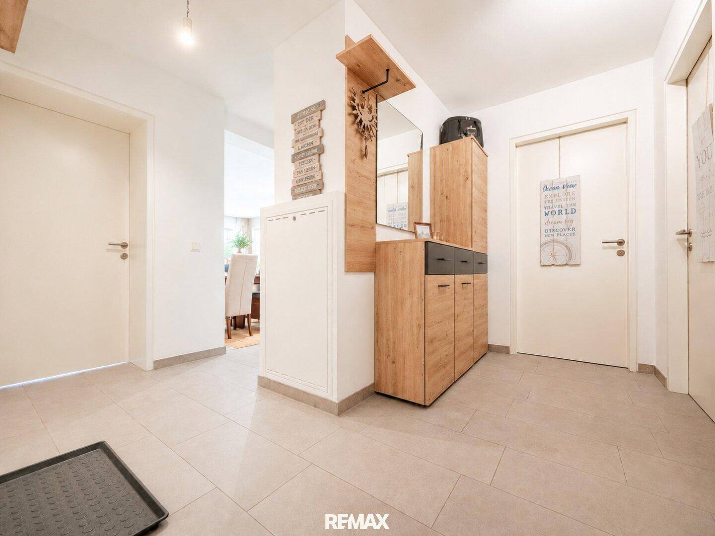 Heller Eingangsbereich mit Fliesenboden und praktischer Garderobe aus Holz und Spiegel.
