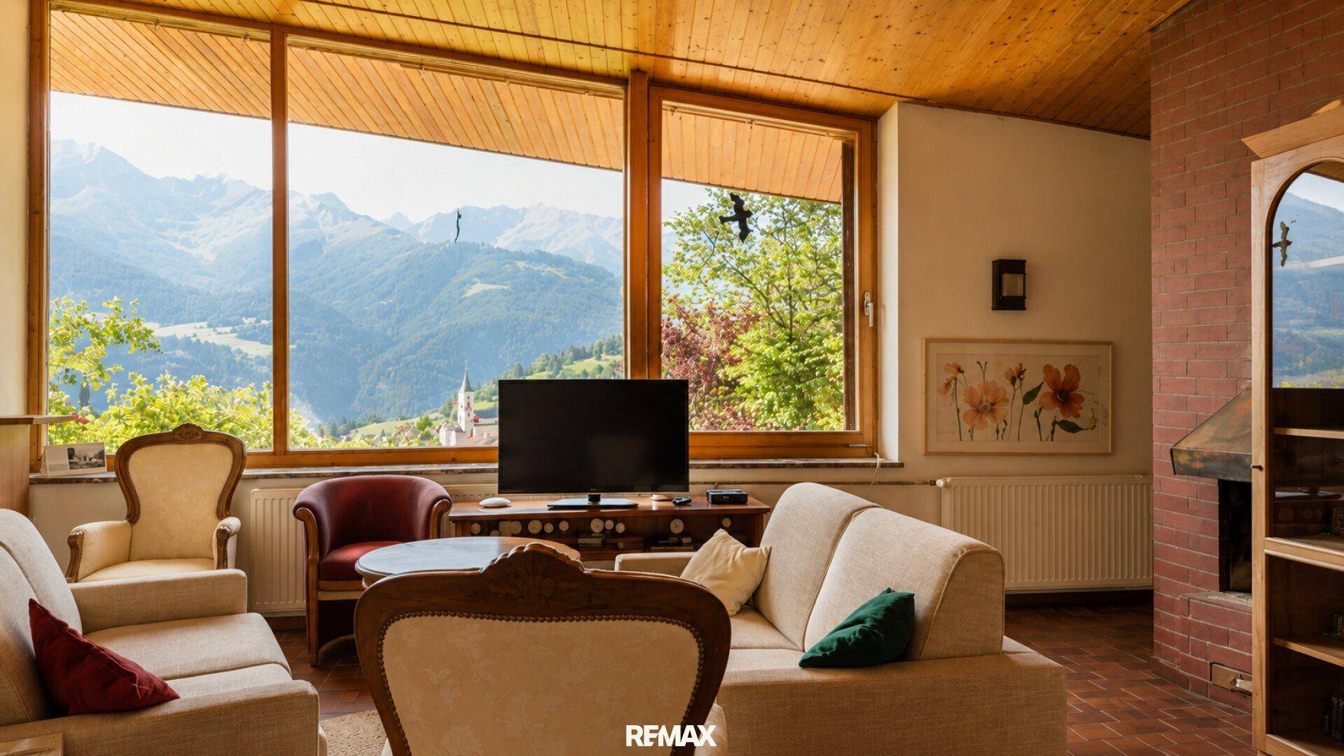 Gemütliches Wohnzimmer mit großen Fenstern, die einen beeindruckenden Blick auf die Bergwelt freigeben.