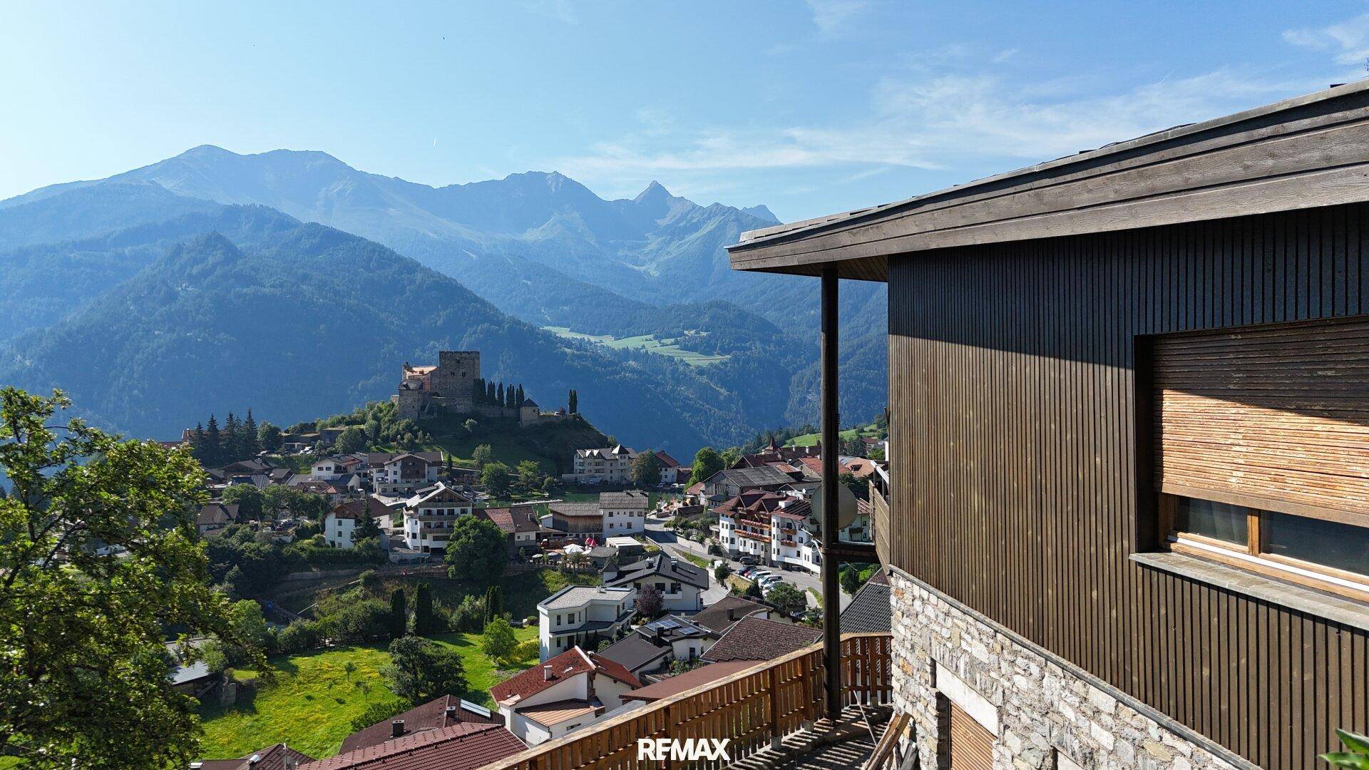 Kleiner Balkon am Haus mit beeindruckendem Panoramablick auf das Tal und ein historisches Dorf.