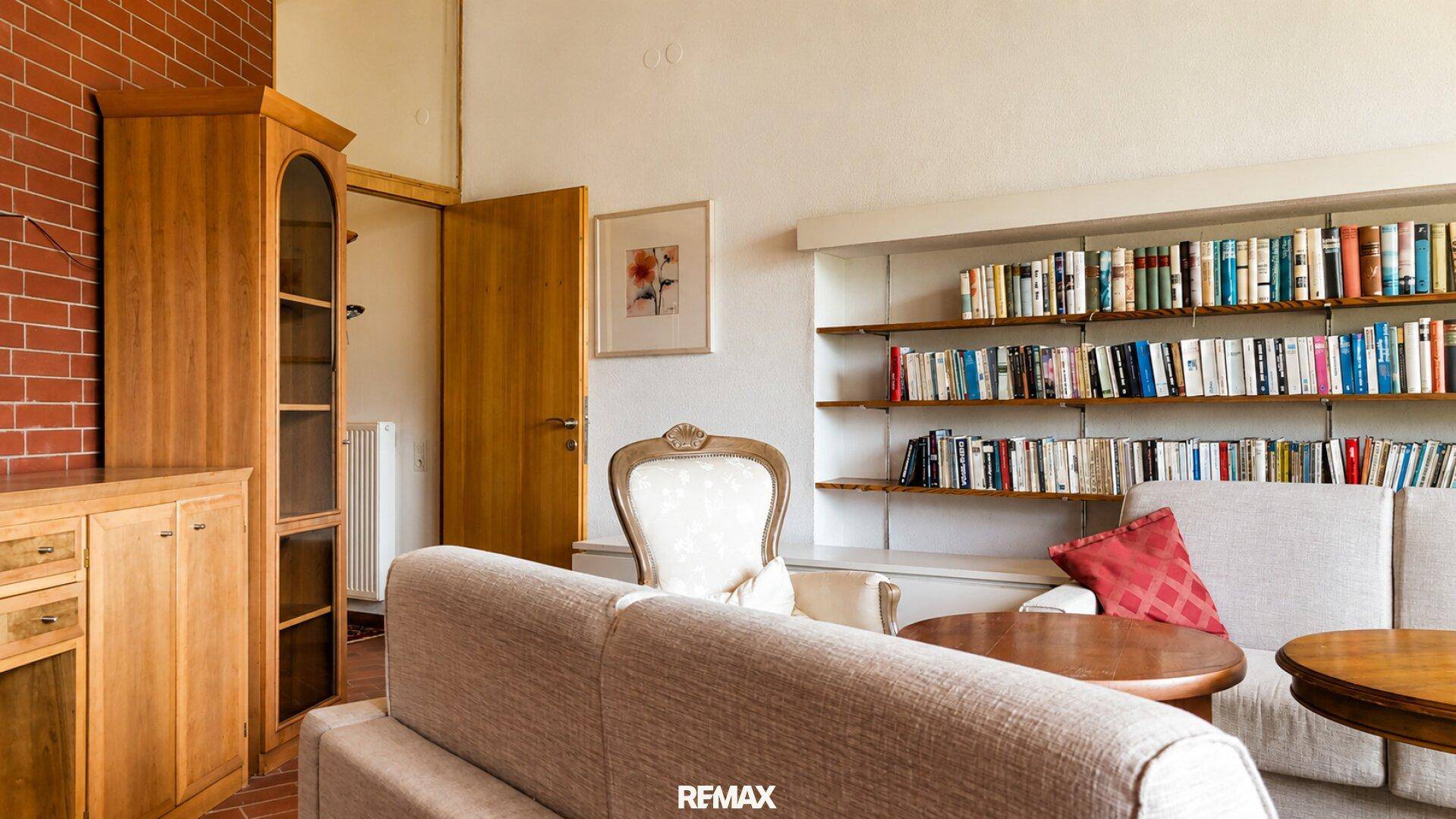Wohnzimmer mit gemütlichem Sofa, Holztisch und einer umfangreichen Bücherwand.