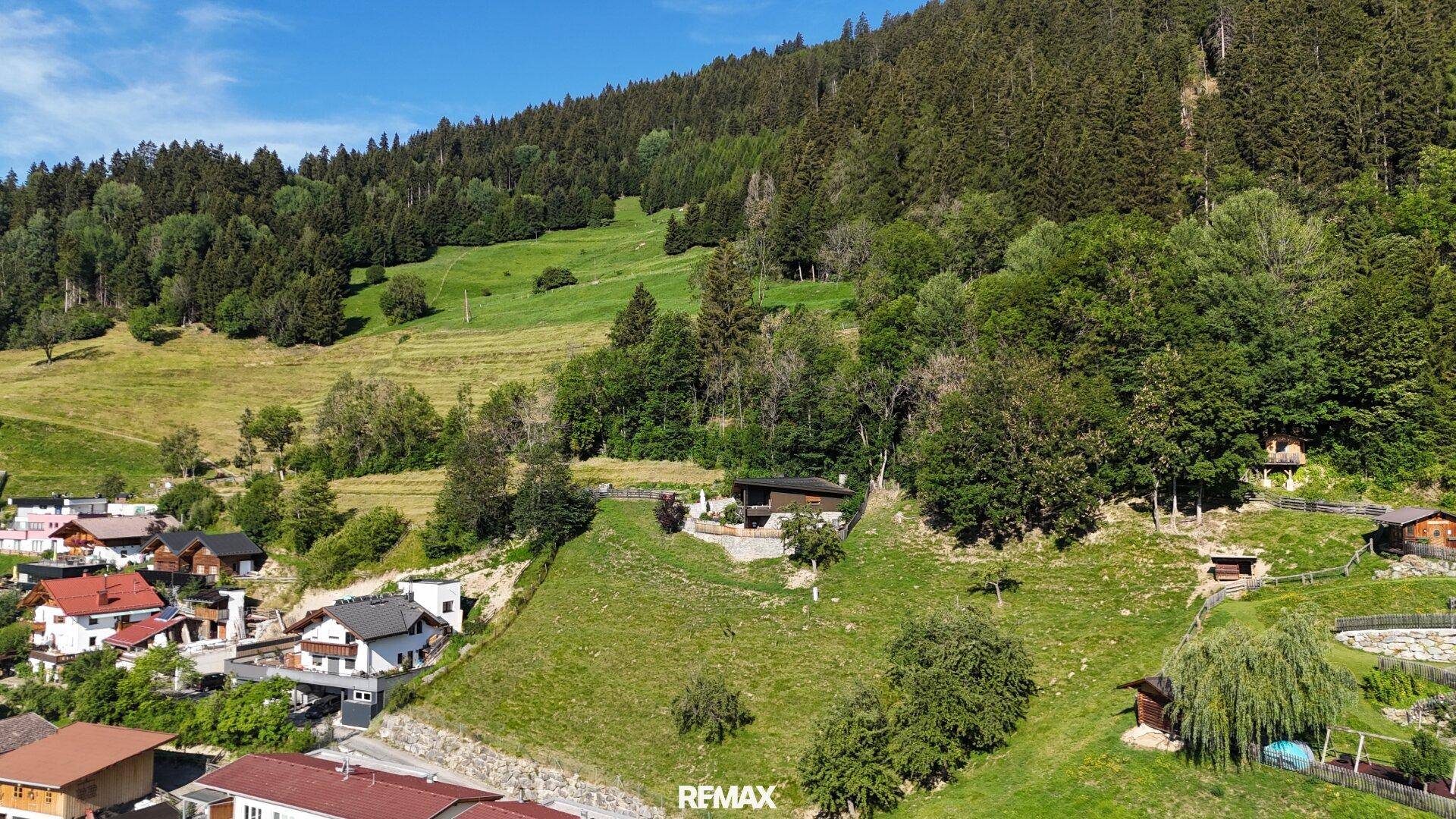 Luftaufnahme des Anwesens, eingebettet in eine grüne, bewaldete Hanglandschaft.