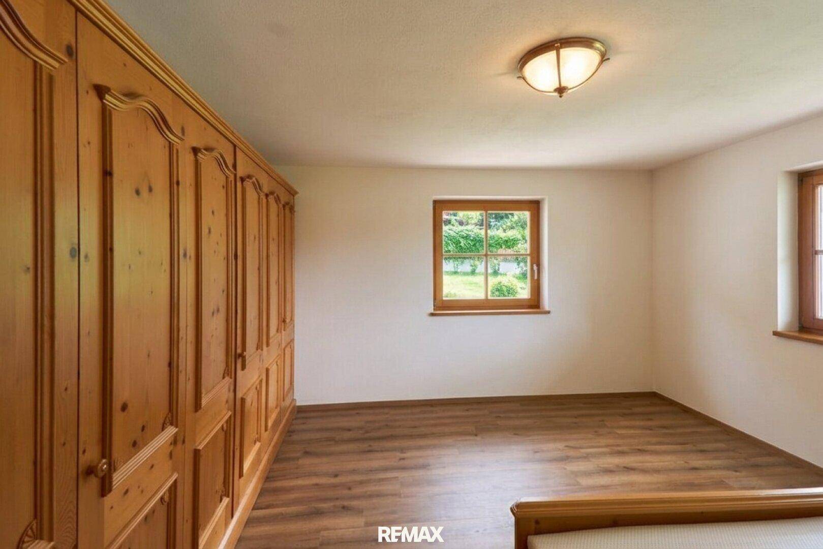 Geräumiges Schlafzimmer mit Holzlaminatboden und großen Einbauschränken aus Holz.