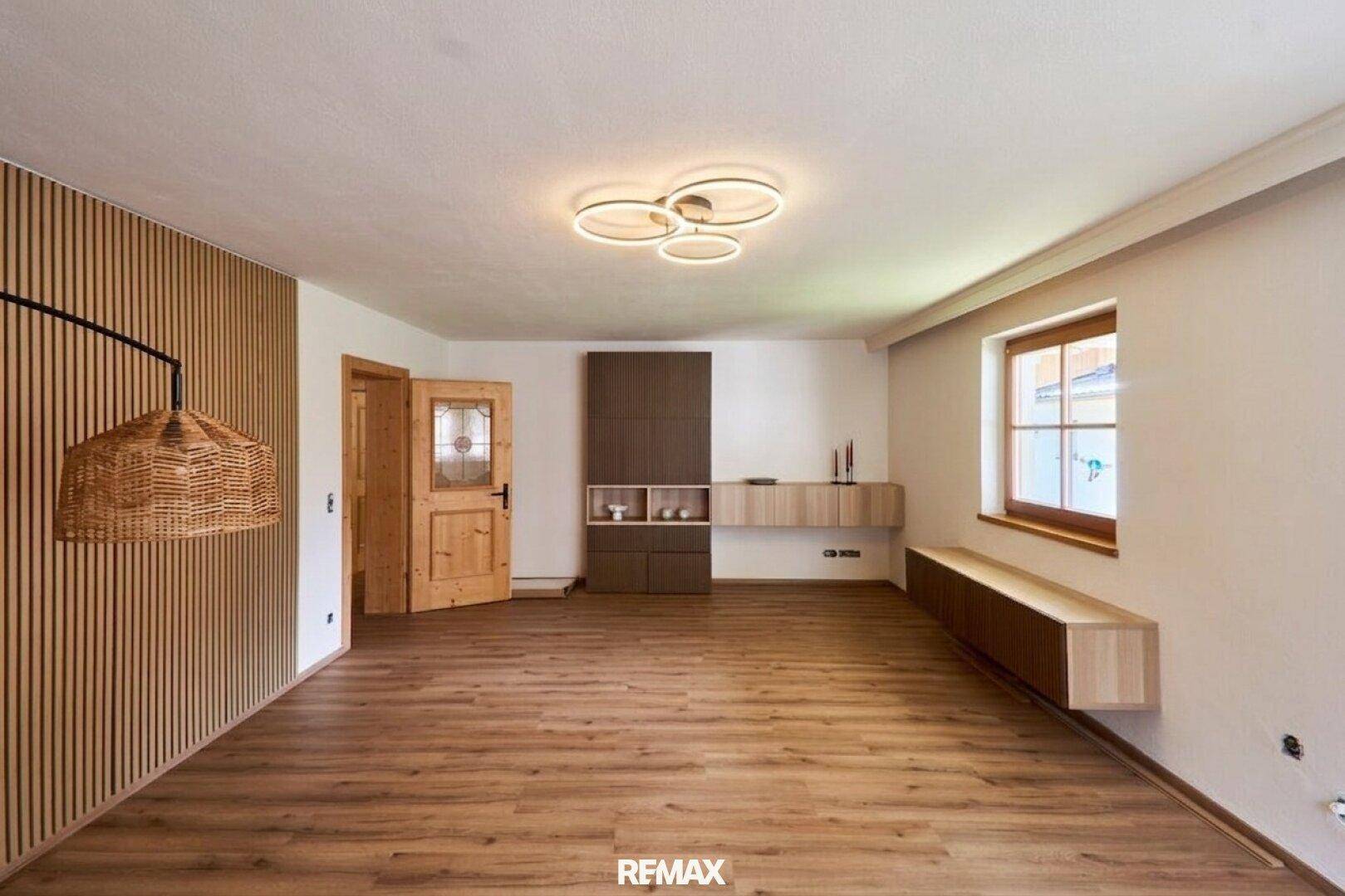 Heller Wohnbereich mit Holzlaminatboden, moderner Wandverkleidung und dekorativer Beleuchtung.