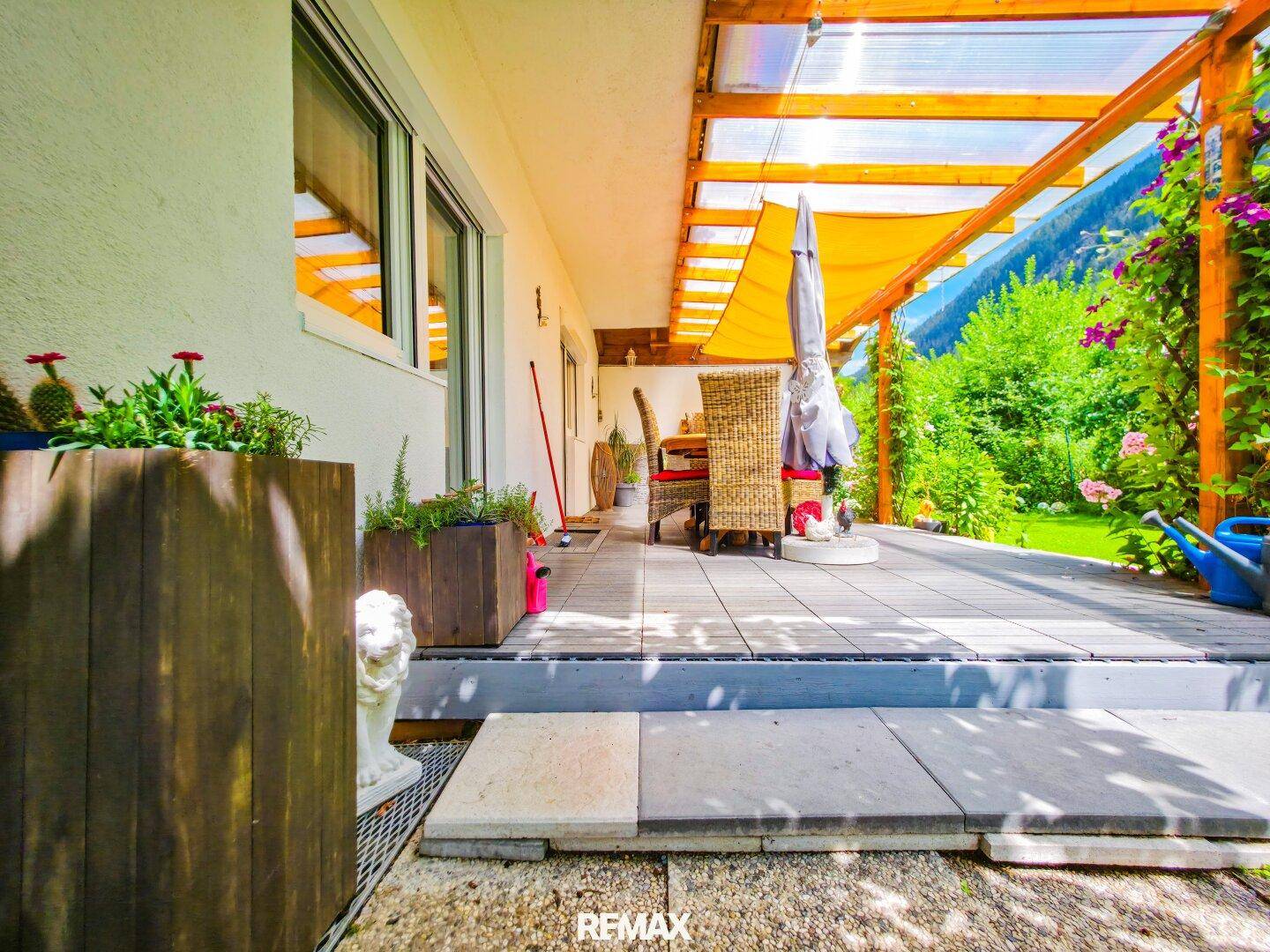 Überdachte Terrasse mit Holzboden und Sitzgelegenheiten, ideal für entspannte Stunden im Freien.