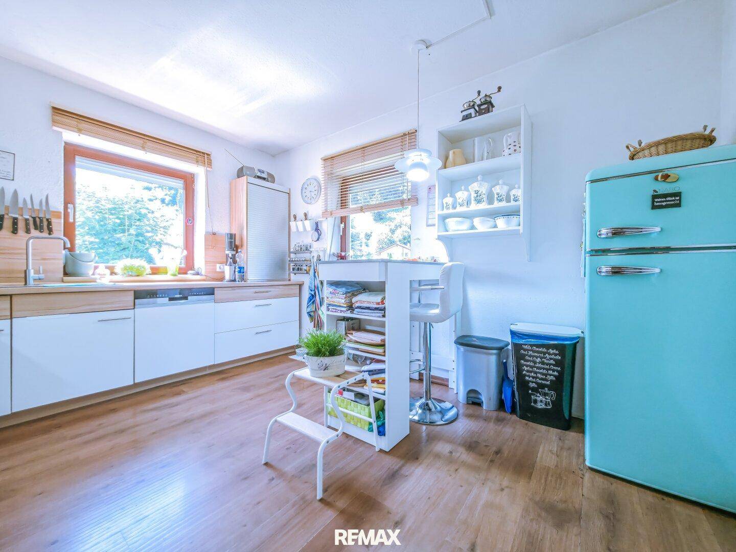 Geräumige Küche mit Essbereich, Retro-Kühlschrank und viel Tageslicht durch große Fenster.