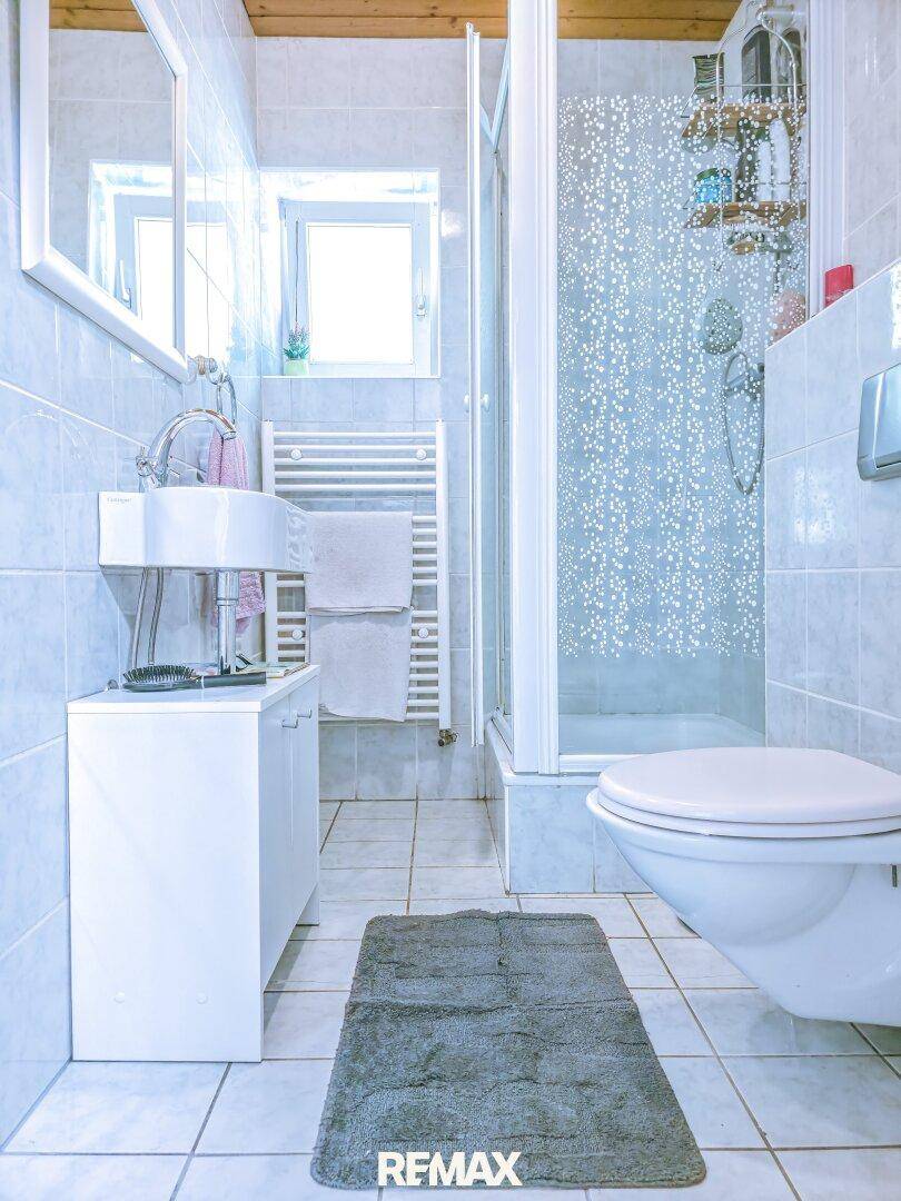Modernes Badezimmer mit Dusche, Einzelwaschbecken und beheiztem Handtuchhalter.