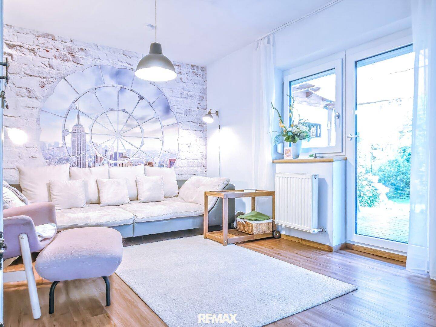 Gemütliches Wohnzimmer mit Sofa, Holzboden und Zugang zu einem Außenbereich.