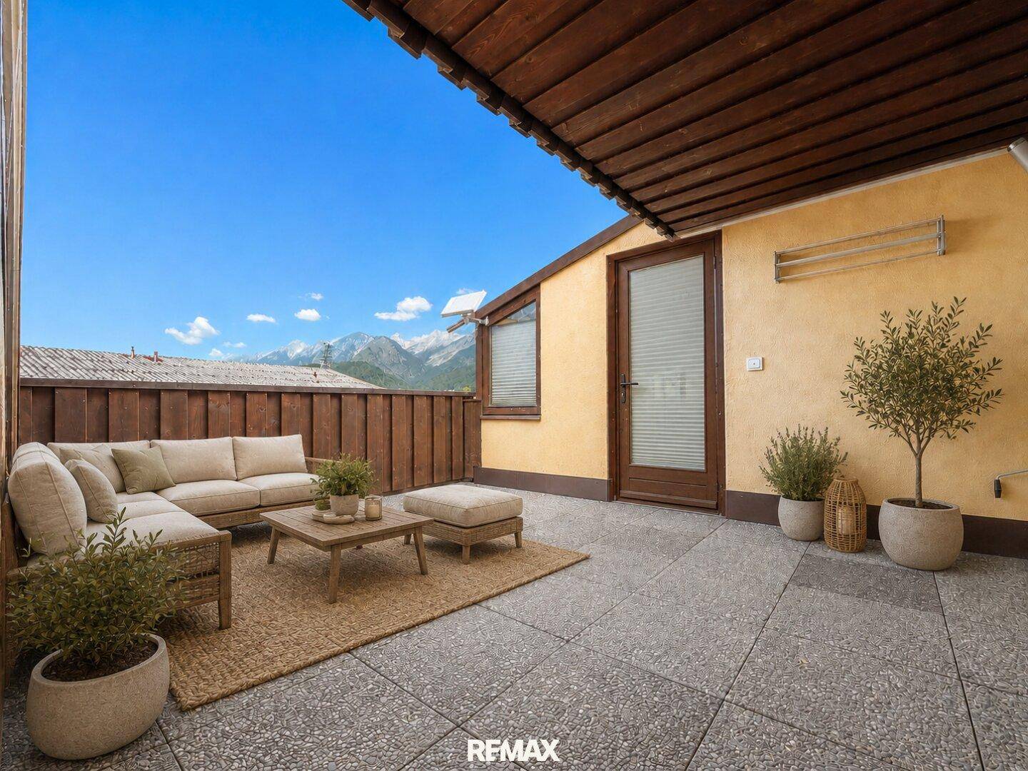 Geräumige Dachterrasse mit bequemen Loungemöbeln, Pflanzen und einem weiten Bergblick.