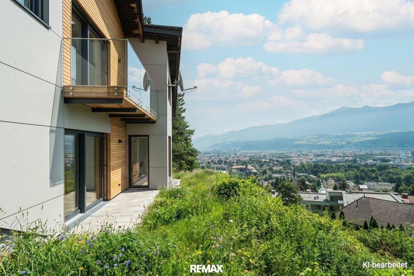 Seitenansicht des modernen Hauses mit Balkon und weitem Blick über die Stadt und die Berge.