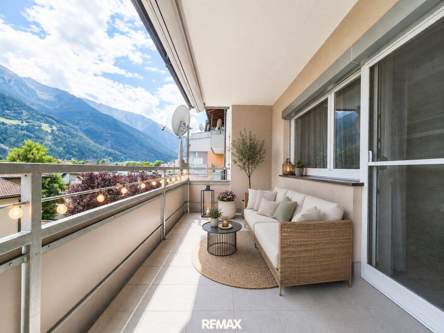 Geräumiger Balkon mit bequemen Outdoor-Möbeln, Lichterkette und atemberaubendem Bergblick.
