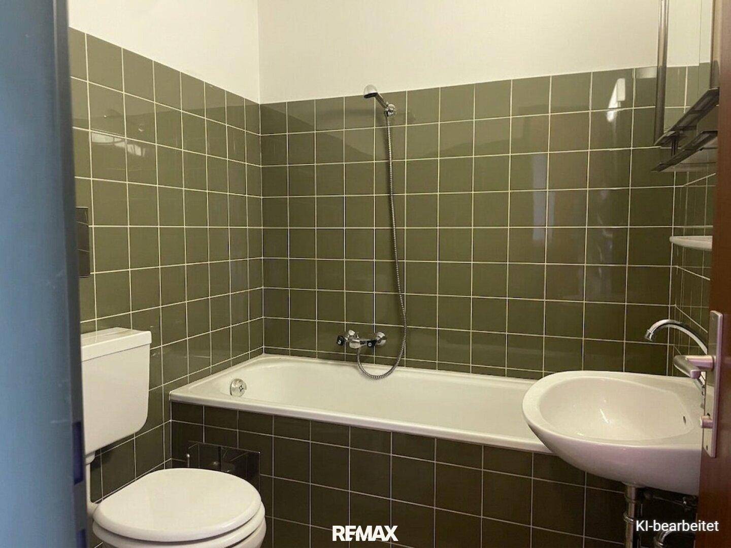 Badezimmer mit grünen Fliesen, Badewanne, Toilette und Waschbecken im Stil der 80er Jahre.