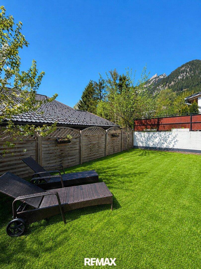 Gepflegter Gartenbereich mit Sonnenliegen und Blick auf die umliegende Berglandschaft.