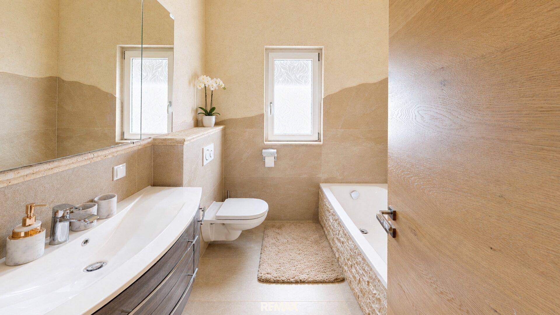 Modernes Badezimmer mit Badewanne, Einzelwaschbecken und Fenster für Tageslicht.
