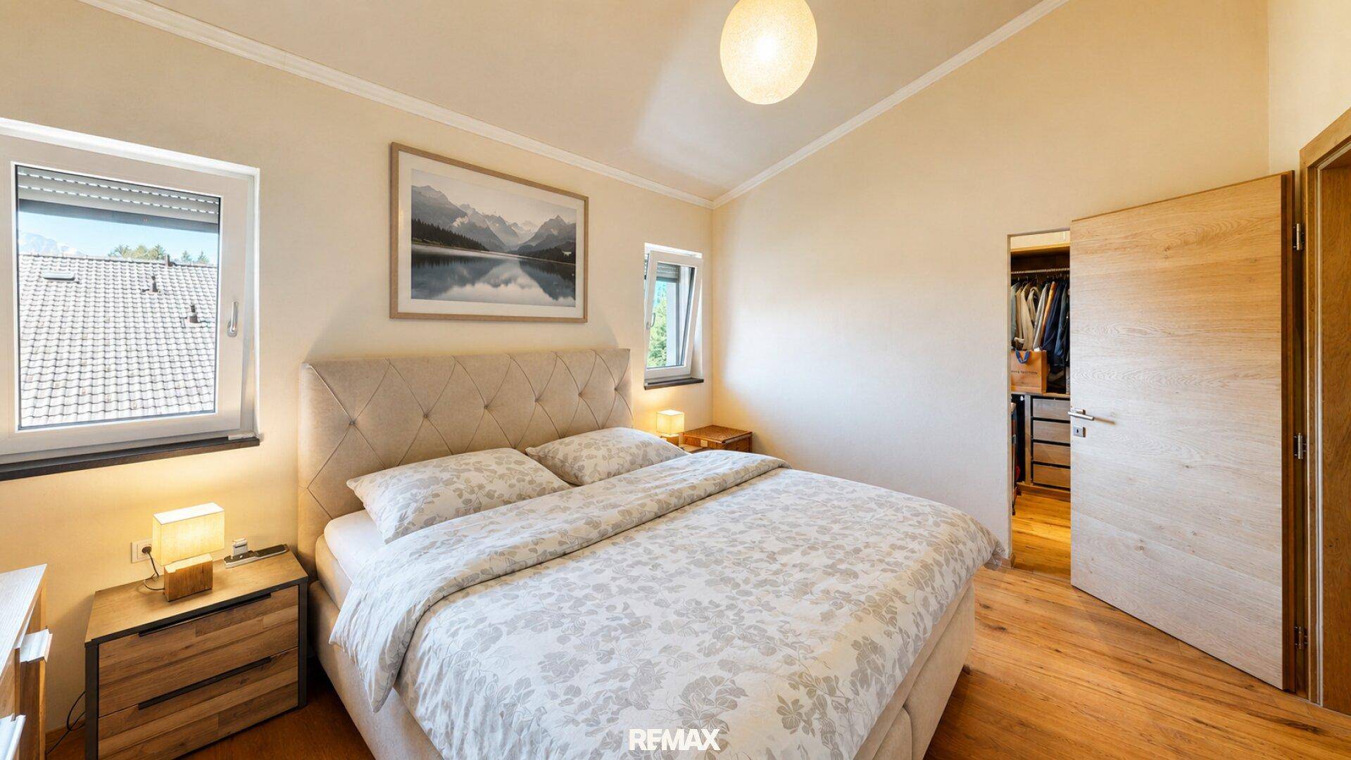 Geräumiges Schlafzimmer mit Doppelbett, Holzboden und Zugang zu einem begehbaren Kleiderschrank.